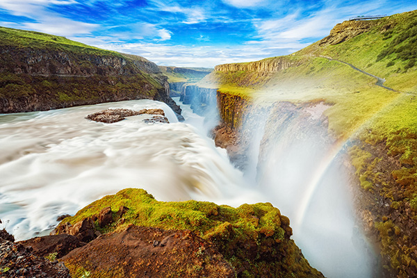 Gullfoss Waterfall, Iceland: A breathtaking view of Iceland’s most powerful waterfall, and one of Europe’s mightiest, adorned with a vibrant rainbow. A picturesque summer scene showcasing the beauty of this iconic Icelandic landmark.